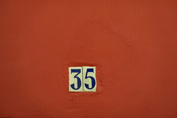 Numéro 35. Plaque de numéro de rue. Mur ocre.