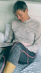 Young intelligent woman in bed with a book in her hand.Girl in bed reading.Fifty year old relaxing...