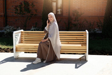 happy muslim female in headscarf calling on phone	