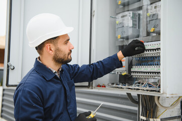 Joyful electrician mounting electric switchboard outdoors