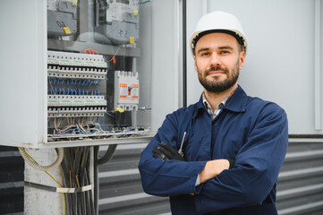 Joyful electrician mounting electric switchboard outdoors
