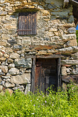 Old stone barn with wooden door and window showing weathering in the Pyrenees mountains, France