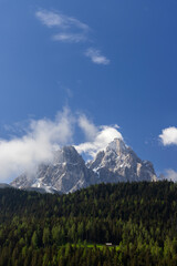 Tre Cime di Lavaredo rising above the coniferous forest in San Candido, Italy