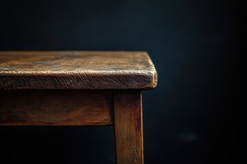 Close-up of a weathered wooden table corner against a dark backdrop.  The table's surface shows signs of age and use.  Simple, rustic design