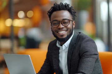 Obraz premium Smiling African American businessman using laptop in modern office.