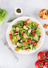 Lebanese fattoush salad with fresh vegetables, romaine lettuce and pita bread on white background. Top view.
