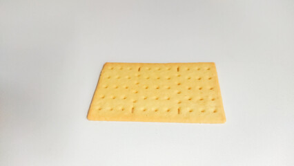 Top-down view of a single rectangular plain biscuit with small evenly spaced holes, placed on a clean white background. The image highlights simplicity and minimalism, ideal for food packaging mockups