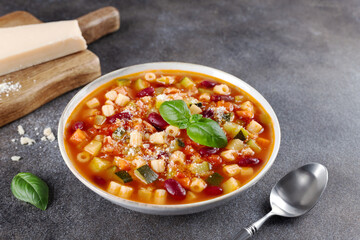 Italian vegetable soup Minestrone with pasta and parmesan cheese on gray background. Italian food.