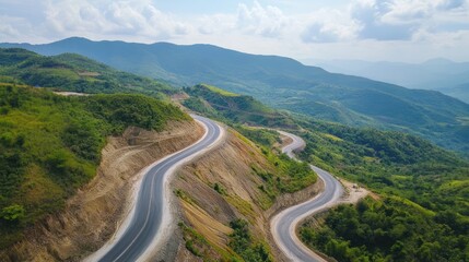 Scenic mountain highway with winding road through lush green landscape aerial view