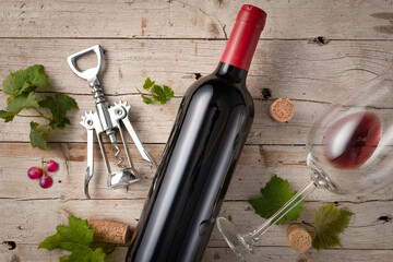 Flat lay composition of bottle and wine glass with open corks and vine leaves.