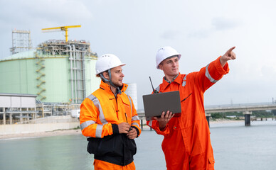 Engineers collaborate on a project near a gas processing facility during a cloudy day at the...