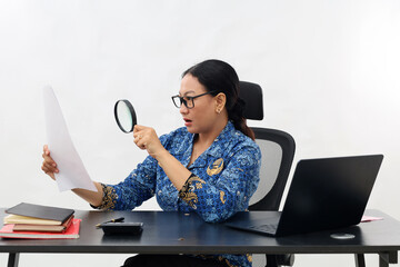 Curious civil servant woman office worker looking at report paper display through magnifying glass,...