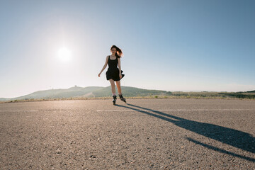 Obraz premium Woman roller skating on road in sunny day, leisure activity