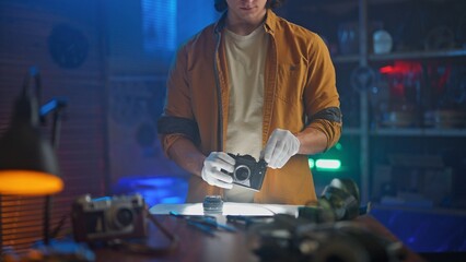 Man Examining Vintage Camera with Precise Care