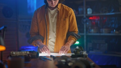 Young Man Studies Film Strip Under Soft Light in Dark Room