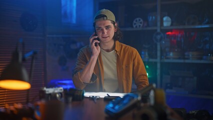 Young Man in Workshop Talking on the Phone at Night