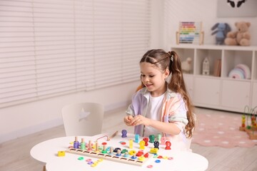 Fototapeta premium Motor skills development. Little girl playing with math game Fishing for Numbers at white table indoors