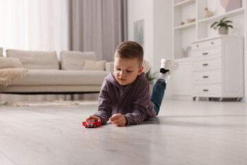 Naklejka premium Little boy playing with toy car at home