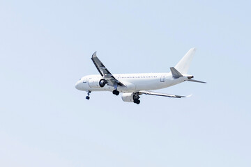 Commercial airplane approaches landing at a sunny airport location during daytime.