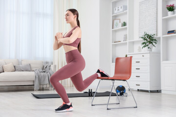 Obraz premium Beautiful woman exercising with chair at home