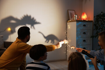 Parents performing shadow play with toy dinosaurs to their kids at home