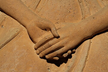 Mains qui se serrent. Détail de bas relief en pierre.