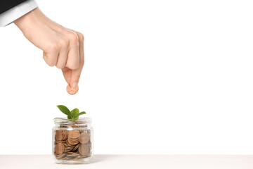 Investment concept. Woman putting coin into glass jar at white table against light background,...
