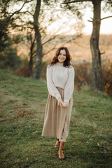 Smiling woman enjoying autumn day in nature wearing sweater and skirt