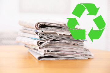 Recycling symbol and stack of many newspapers on wooden table, closeup. Eco-friendly lifestyle,...