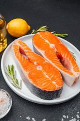 Fresh salmon fillets ready for cooking with lemon and herbs on a plate