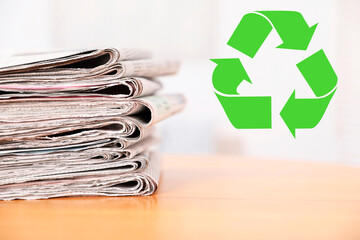 Recycling symbol and stack of many newspapers on wooden table, closeup. Eco-friendly lifestyle,...