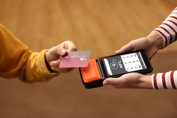 Payment terminal with NFC system. Client using credit card to pay for service indoors, closeup