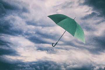 Green umbrella flying in cloudy sky under heavy rain. Stormy weather