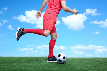 Football player kicking soccer ball under blue sky, closeup
