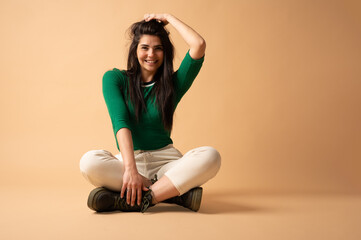 Young woman sitting cross-legged touching her hair and smiling