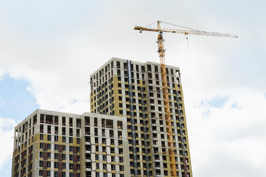 New skyscraper under construction with construction crane against cloudy sky. Highrise Building Site.
