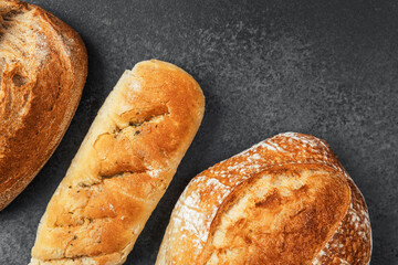 Freshly baked artisan bread varieties displayed on dark surface
