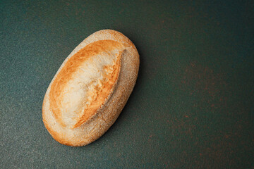 Freshly baked roll rests on a dark surface with a golden crust and soft texture