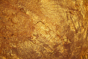 Closeup of golden fluid metallic acrylic paint textured background