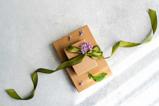 Elegant gift boxes with green ribbon and purple flowers