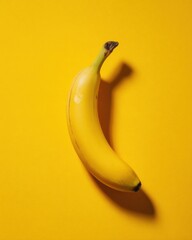 Single ripe banana casting shadow on bright yellow background overhead shot studio lighting minimalist food photography