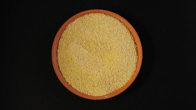 Fenugreek powder or Hulbah in clay plate. Crushed fenugreek seeds. Healthy seeds of plant Trigonella foenum-graecum uses in culinary and alternative medicine.