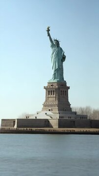 Statue of Liberty featuring a neoclassical sculpture on Liberty Island, with people standing on the perimeter wall on a clear day
