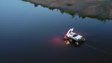 An aerial perspective of the rover navigating a serene dockside landscape illustrating its dual capabilities on land and in water while surveying potential threats.