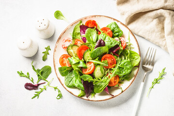 Salad from green leaves and vegetables on white.