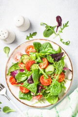 Salad from green leaves and vegetables on white.