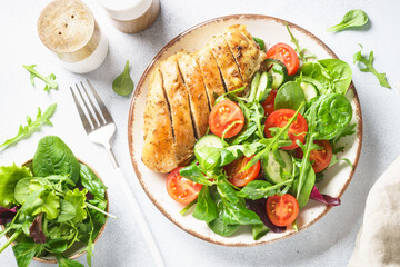 Green salad with chicken fillet on white.