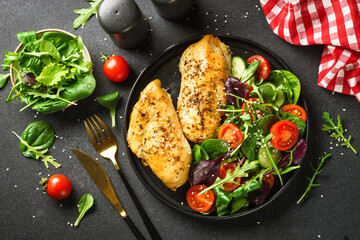 Green salad with chicken fillet on black.
