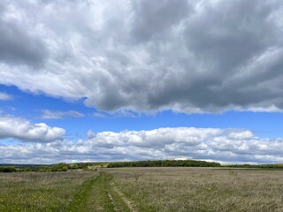 Vast open field under blue sky with clouds, tranquility and depth
