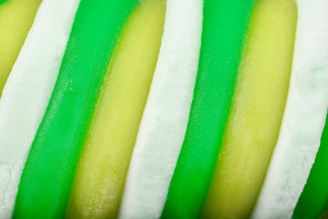 A macro shot reveals swirling horizontal bands of bright green, pale yellow, and white ice cream